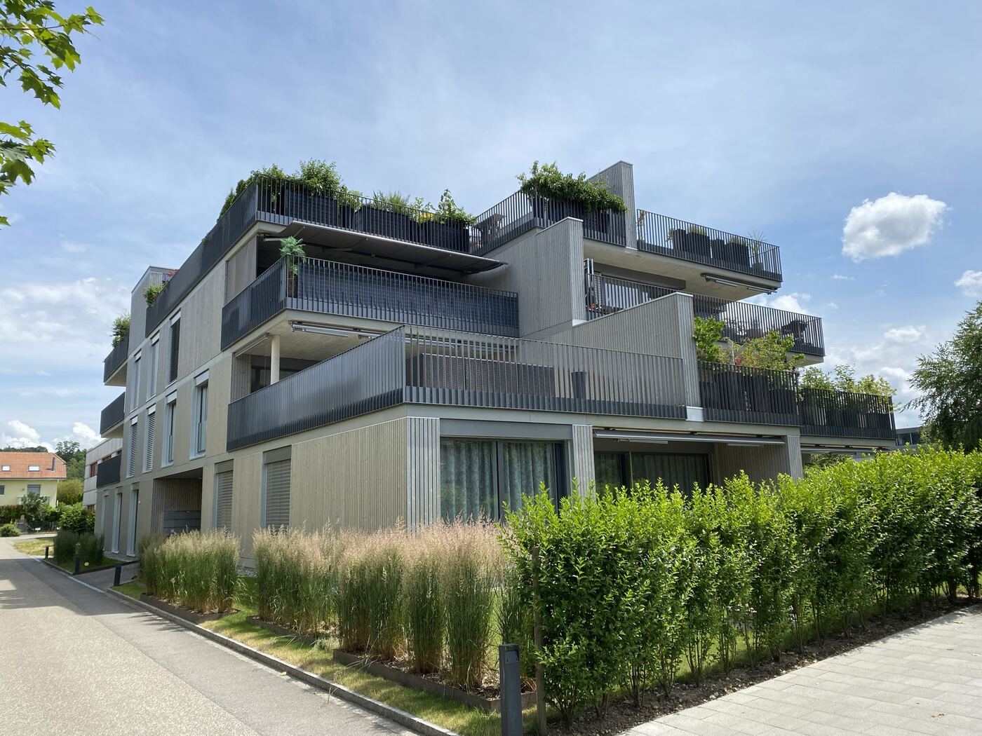Fassade Les Terrasses mit Holzlamellen und begrünten Terrassen